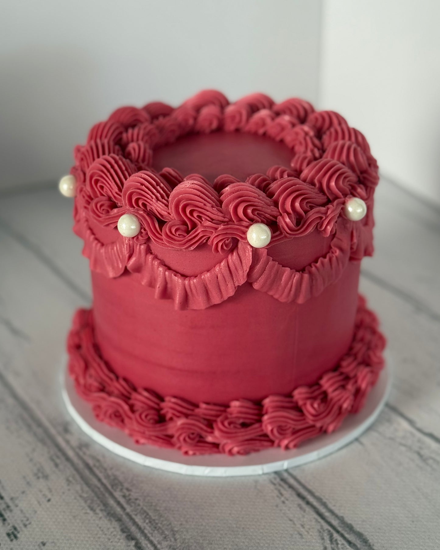 Red frosted cake with decorative ruffles and pearls 
