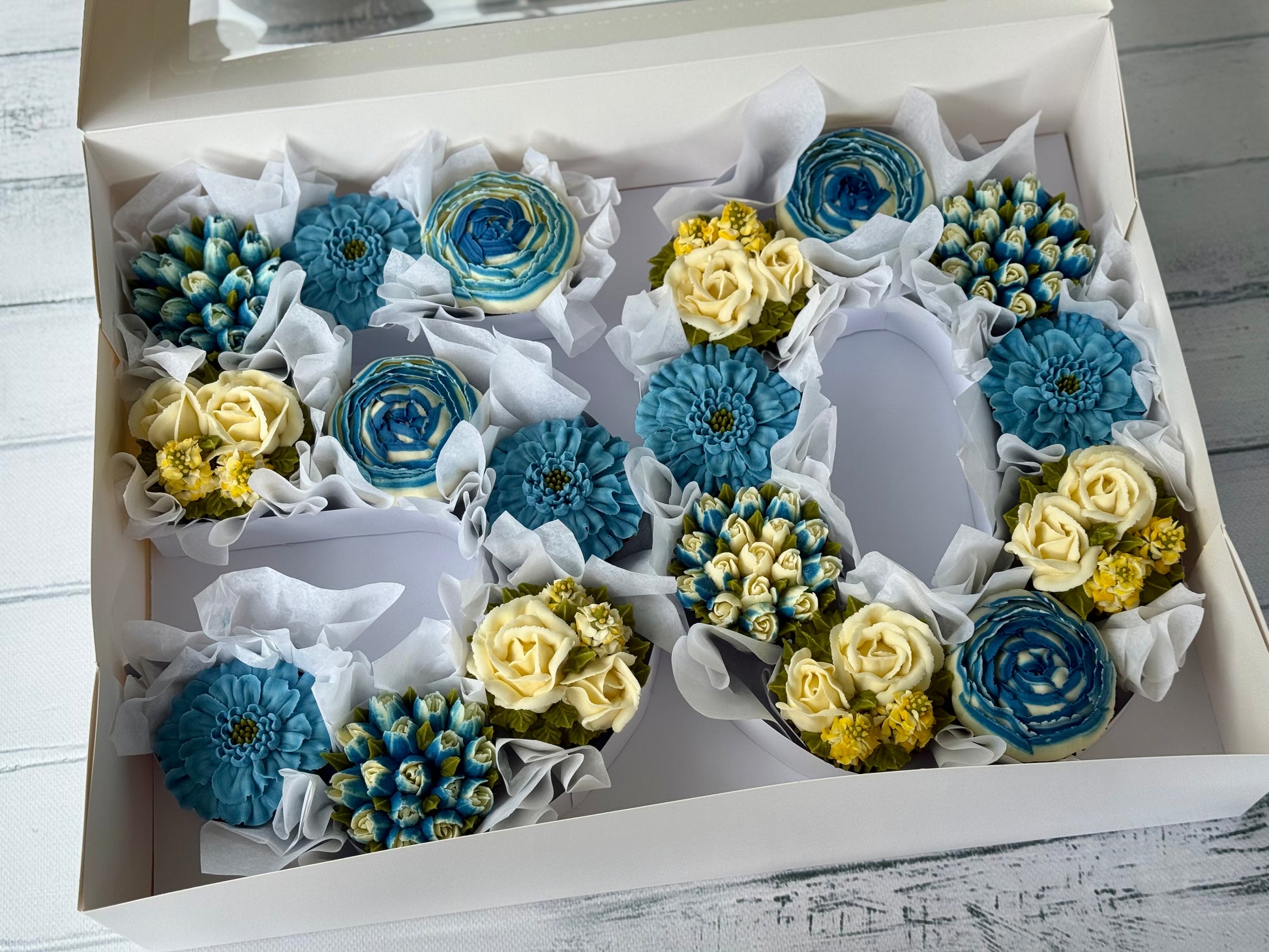 Floral cupcakes of blue and yellow flowers in a number box.
